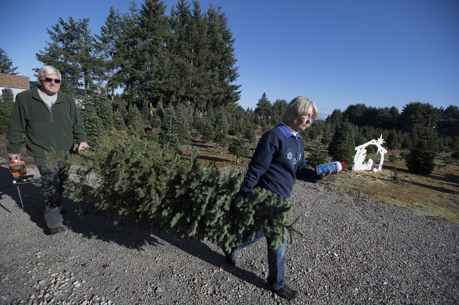 Loran, left, and Jane Larwick, both 65, haul what they say is an unsellable tree to be used instead for photo ops in Jane&#039;s shop. The two have run the 20-acre U-cut tree farm for 25 years, having lived at the property for just over 30 years.