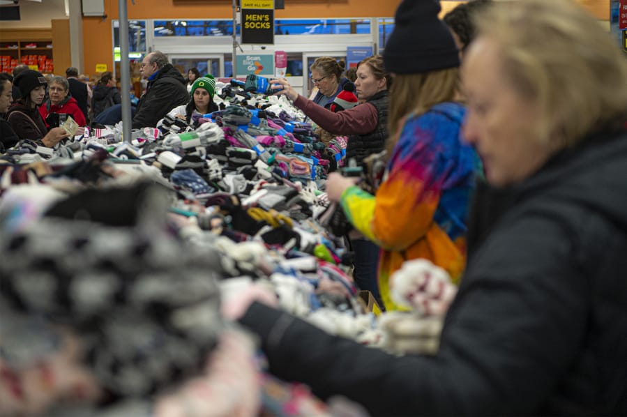 Shoppers search through piles of socks during the Black Friday sock sale at Fred Meyer on Friday morning. The department store chain expects to sell more than a million pairs of socks in total on Black Friday.