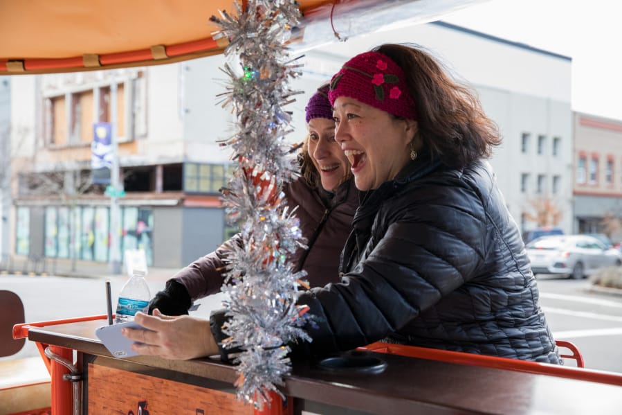 Michele Thayer, left, and Jeannie Jacobs laugh while taking a selfie on the Couve Cycle party bike Saturday afternoon in downtown Vancouver.