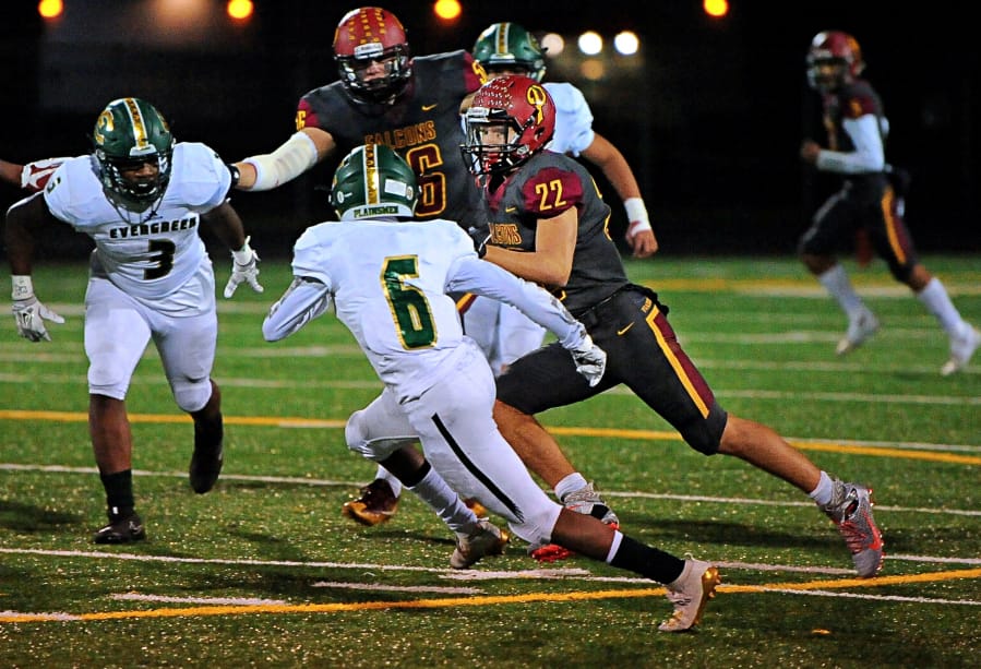 Prairie running back Dustin Shelby ran for 141 yards on 17 carries, including this run past Evergreen&#039;s Jonathan Simon (6) and Derrick Webb (3) in the Falcons&#039; 42-14 win over Evergreen on Friday at District Stadium in Battle Ground. The win secures Prairie&#039;s first league title since 1992.