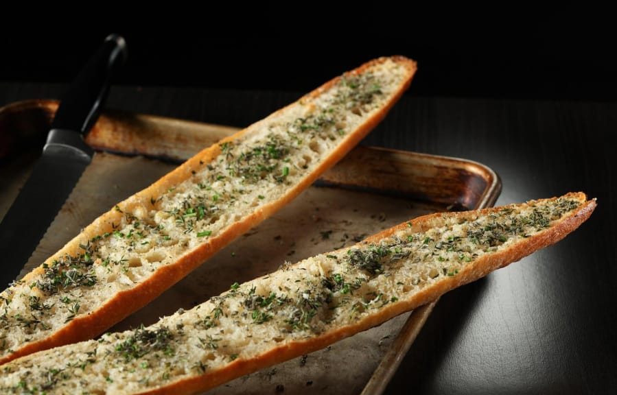 The warm garlic bread is finished with fresh herbs, like sage, thyme, chives and oregano.