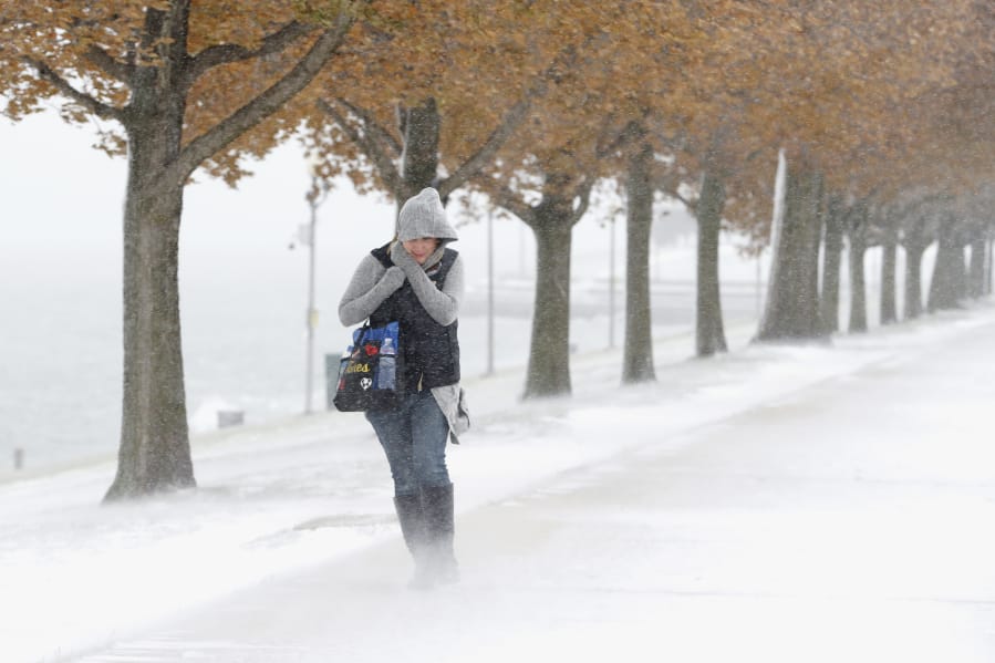A woman is buffeted by the stiff wind and blowing snow off Lake Michigan as she walks Monday in Chicago.