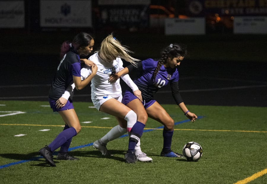 Columbia River's Yaneisy Rodriguez,right, fights for the ball against Ridgefield's Annika Farley, center, during the 2A district championship at Columbia River High School in Vancouver on Nov. 7, 2019. Ridgefield won 2-1.