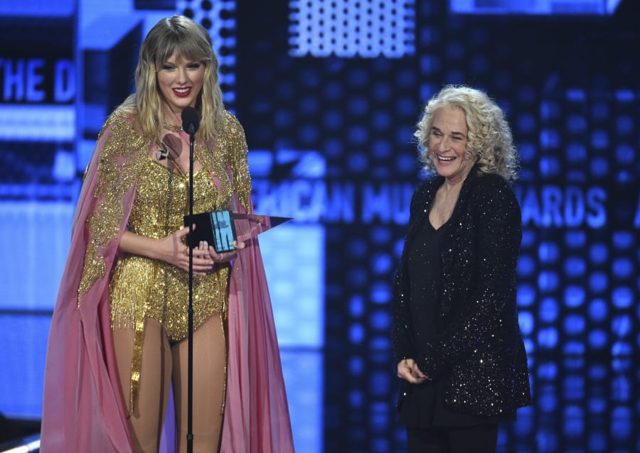 Taylor Swift, left, accepts the award for artist of the decade at the American Music Awards on Sunday, Nov. 24, 2019, at the Microsoft Theater in Los Angeles. Looking on at right is Carole King.