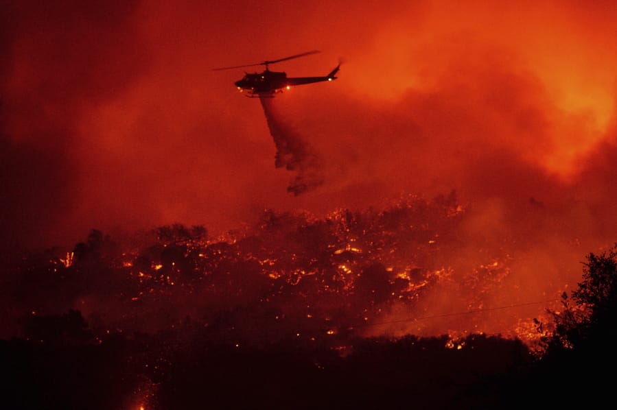 A helicopter drops water on the Cave Fire burning along Highway 154 in Los Padres National Forest, Calif., above Santa Barbara on Tuesday, Nov. 26, 2019.