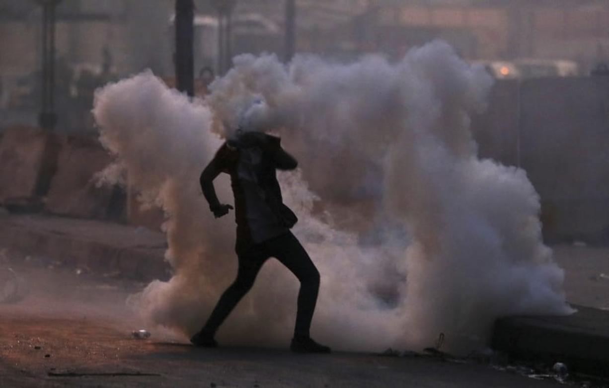 An anti-government protester is surrounded by tear gas fired by Iraqi security forces in an effort to disperse demonstrators, in central Baghdad, Iraq, Sunday, Nov. 10, 2019.
