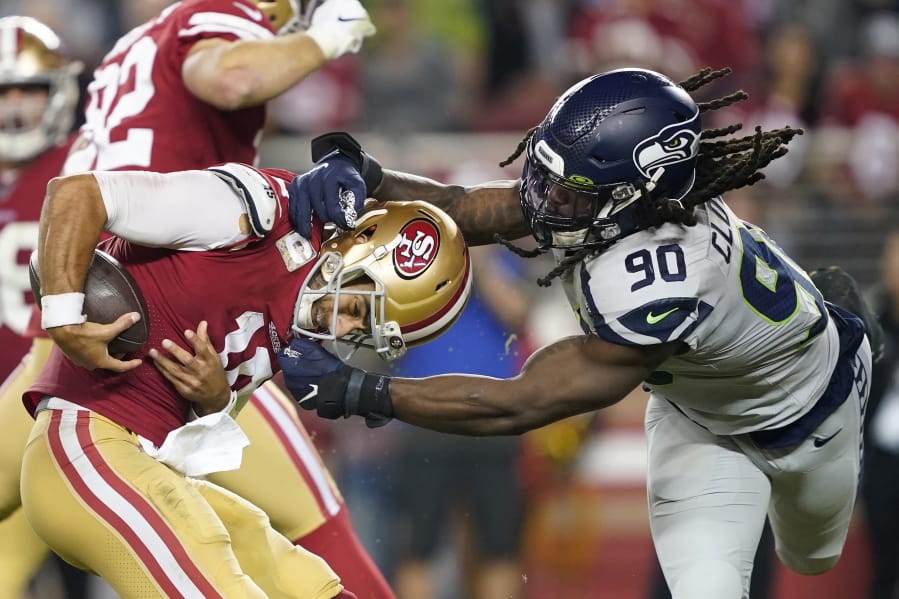 San Francisco 49ers quarterback Jimmy Garoppolo, left, avoids being sacked by Seattle Seahawks defensive end Jadeveon Clowney (90) during the second half of an NFL football game in Santa Clara, Calif., Monday, Nov. 11, 2019.