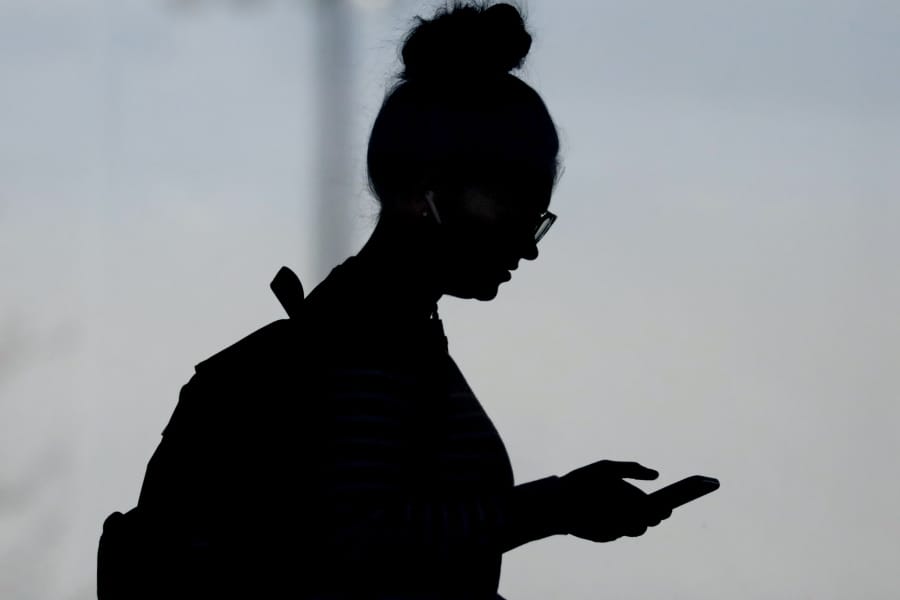 FILE - In this Nov. 14, 2019, file photo, a woman checks her phone in Orem, Utah. A new poll from The Associated Press-NORC Center for Public Affairs Research and USAFacts finds that Americans are getting information about government from social media at least as much as from traditional news sources, but few trust what they see and read.