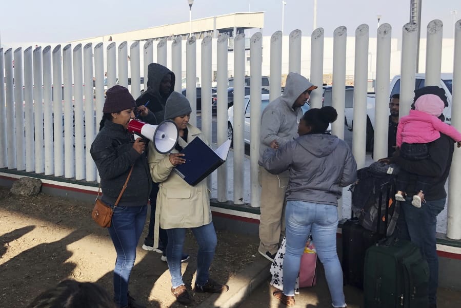 In this Nov. 12, 2019, photo, volunteers call names of people on a waiting list trying to obtain asylum in the United States along the U.S.-Mexico border in Tijuana, Mexico. The U.S. has sent a Honduran migrant back to Guatemala in a move that marked a new phase of President Donald Trump&#039;s immigration crackdown.