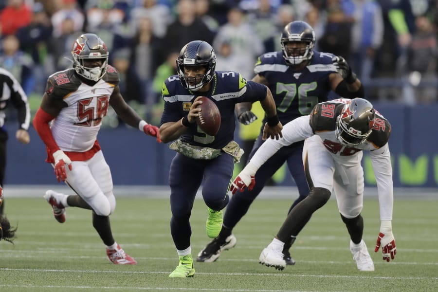 Seattle Seahawks quarterback Russell Wilson (3) scrambles away from Tampa Bay Buccaneers defensive end Jason Pierre-Paul (90) during overtime of an NFL football game, Sunday, Nov. 3, 2019, in Seattle.