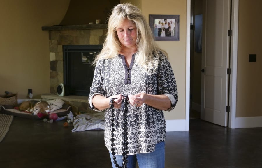 In this Monday, Nov. 4, 2019, photo, Tina Chandler looks through her Kukui Nut Lei, as she recalls packing them with a family portrait when she evacuated with during the Kincade Fire, in the Fountaingrove neighborhood of Santa Rosa, Calif. Two years ago, the Chandlers had only minutes to escape before their longtime family home burned to the ground before their eyes. They rose from the ashes to build a new home. The night of the fire Chandler packed a framed family photo along with a box of kukui nut necklaces that a friend had sent from Hawaii after they lost their home. &quot;I know that sounds kind of silly,&quot; she said of the black shiny nuts, which represent hope and renewal.