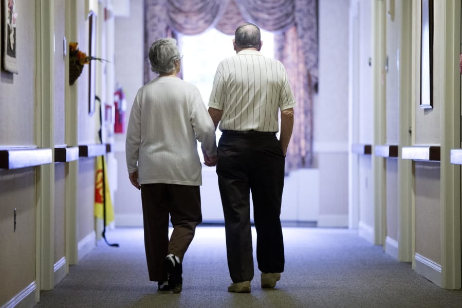 An elderly couple walks down a hall in Easton, Pa. Research released Friday suggests many American adults inaccurately estimate their chances for developing dementia.