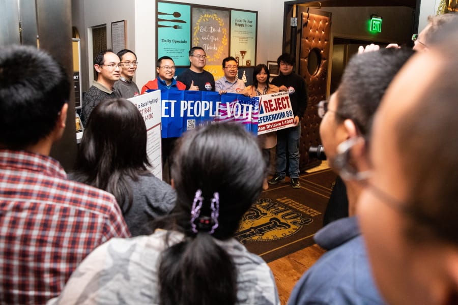 Supporters take photos with their banners and signs as polls show an early lead for the anti-affirmative action group Reject Referendum 88 at their election-watching event at 13 Coins in Bellevue on Tuesday, Nov. 5, 2019.