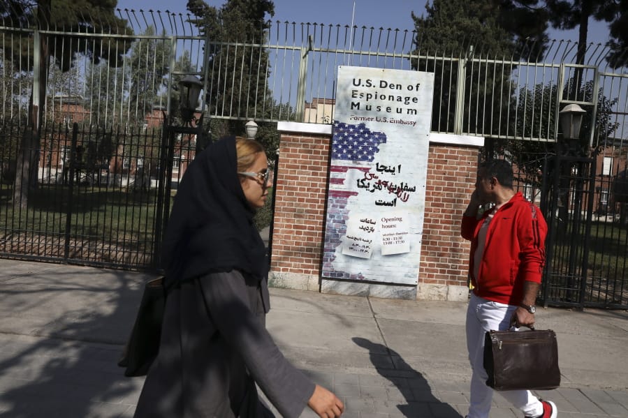 In this Tuesday, Oct. 15, 2019 photo, Iranians walk past anti-U.S. graffiti on the wall of the former U.S. Embassy, in Tehran, Iran. For those who were there, the memories are still fresh 40 years after one of the defining events of Iran&#039;s 1979 Islamic Revolution, when protesters seized the U.S. Embassy in Tehran and set off a 444-day hostage crisis whose consequences continue to reverberate to this day.