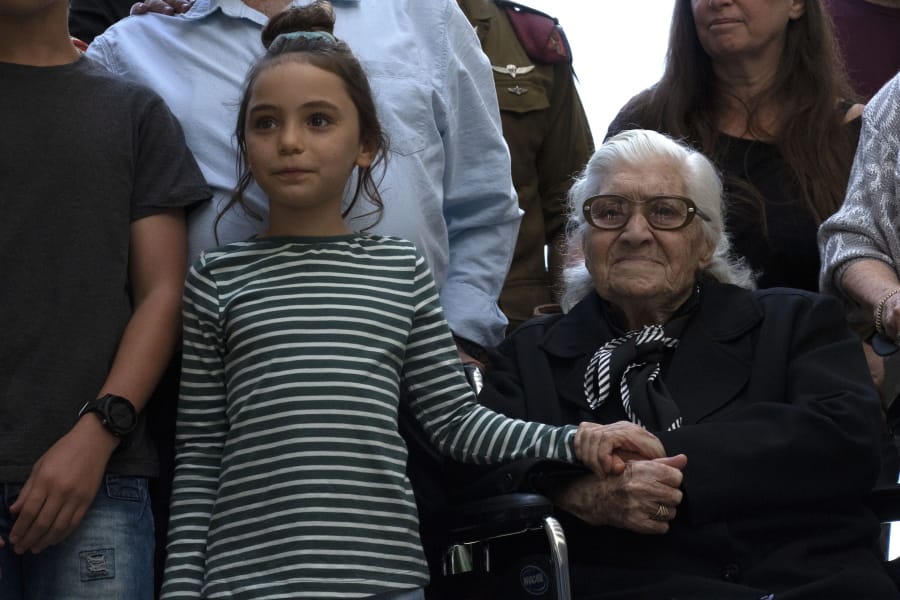 Melpomeni Dina holds the hand of an Israeli girl Sunday during a reunion at the Yad Vashem Holocaust memorial in Jerusalem.