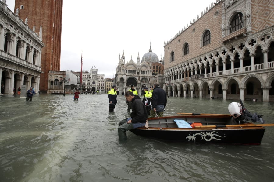 A man sits on a small boat in a flooded St.Mark square in Venice, Italy, Sunday, Nov. 17, 2019. Venetians are bracing for the prospect of another exceptional tide in a season that is setting new records. Officials are forecasting a 1.6 meter (5 feet, 2 inches) surge of water Sunday through the lagoon city.