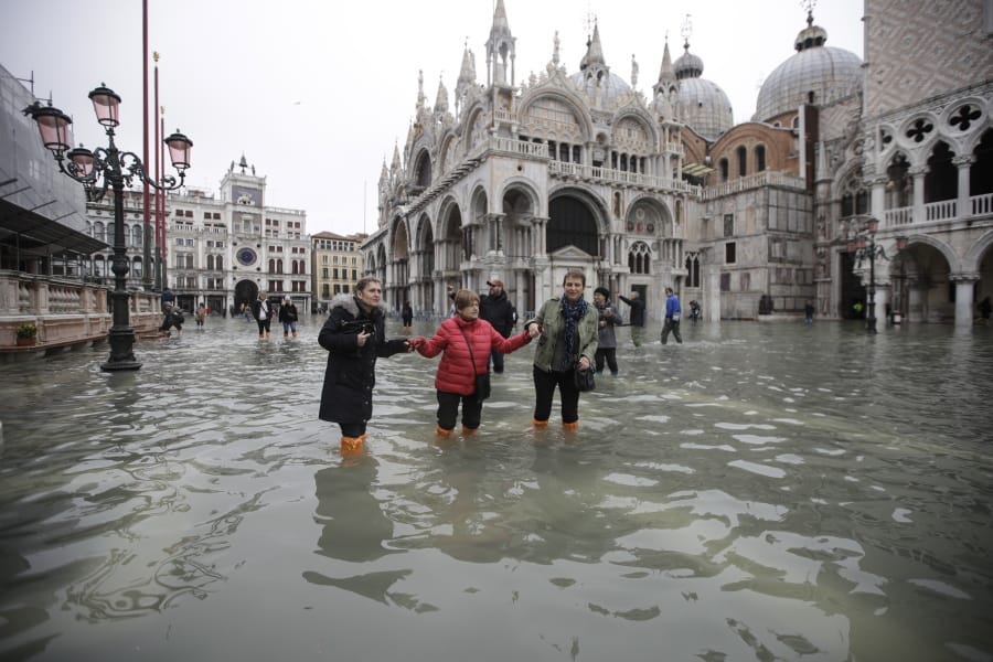 People wade through water in a flooded St. Mark&#039;s Square in Venice, Italy, Wednesday, Nov. 13, 2019. The high-water mark hit 187 centimeters (74 inches) late Tuesday, Nov. 12, 2019, meaning more than 85% of the city was flooded. The highest level ever recorded was 194 centimeters (76 inches) during infamous flooding in 1966.