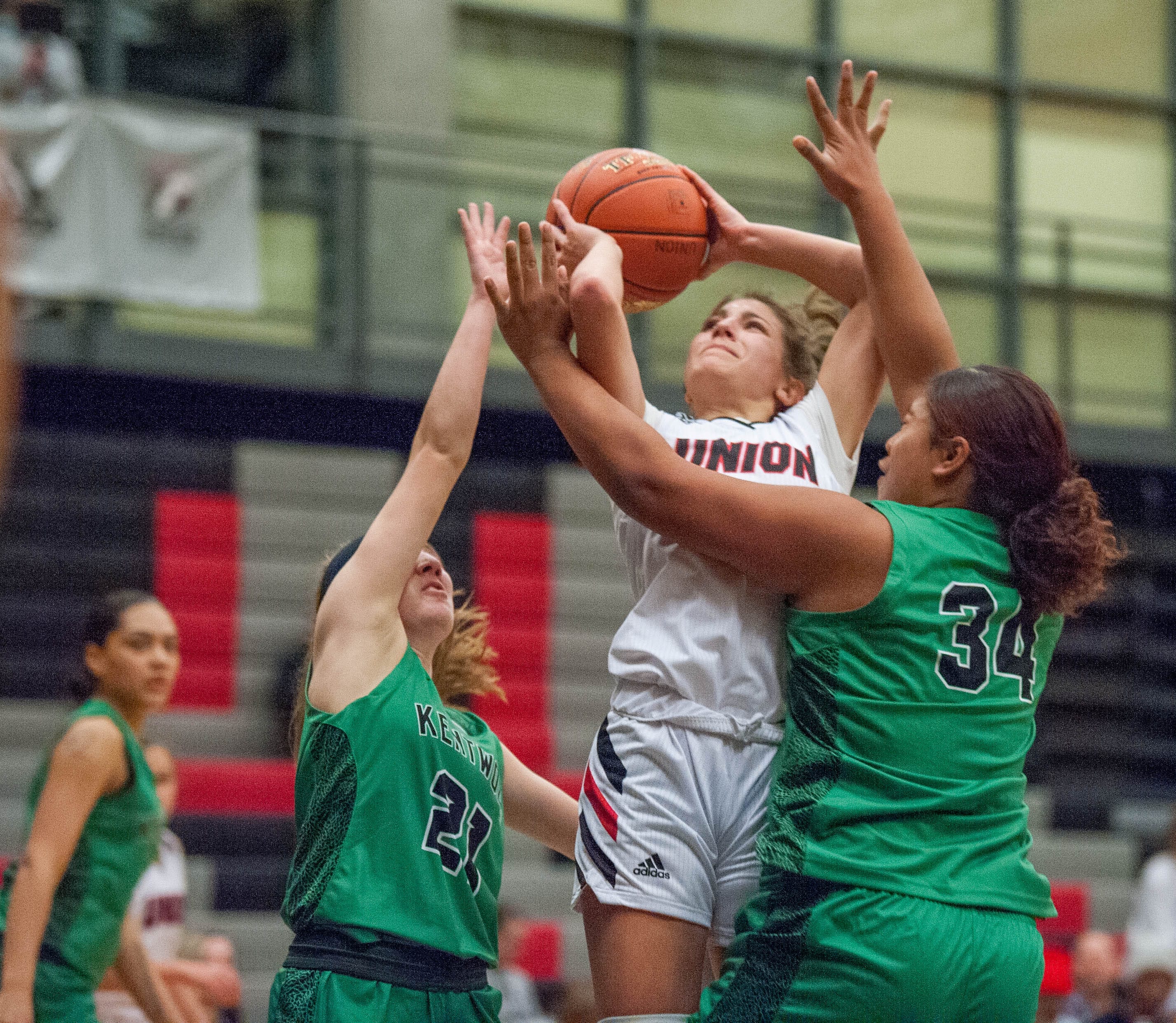 Union's Mason Oberg drives between a pair of Kentwood defenders in a girls basketball game at Union High School.