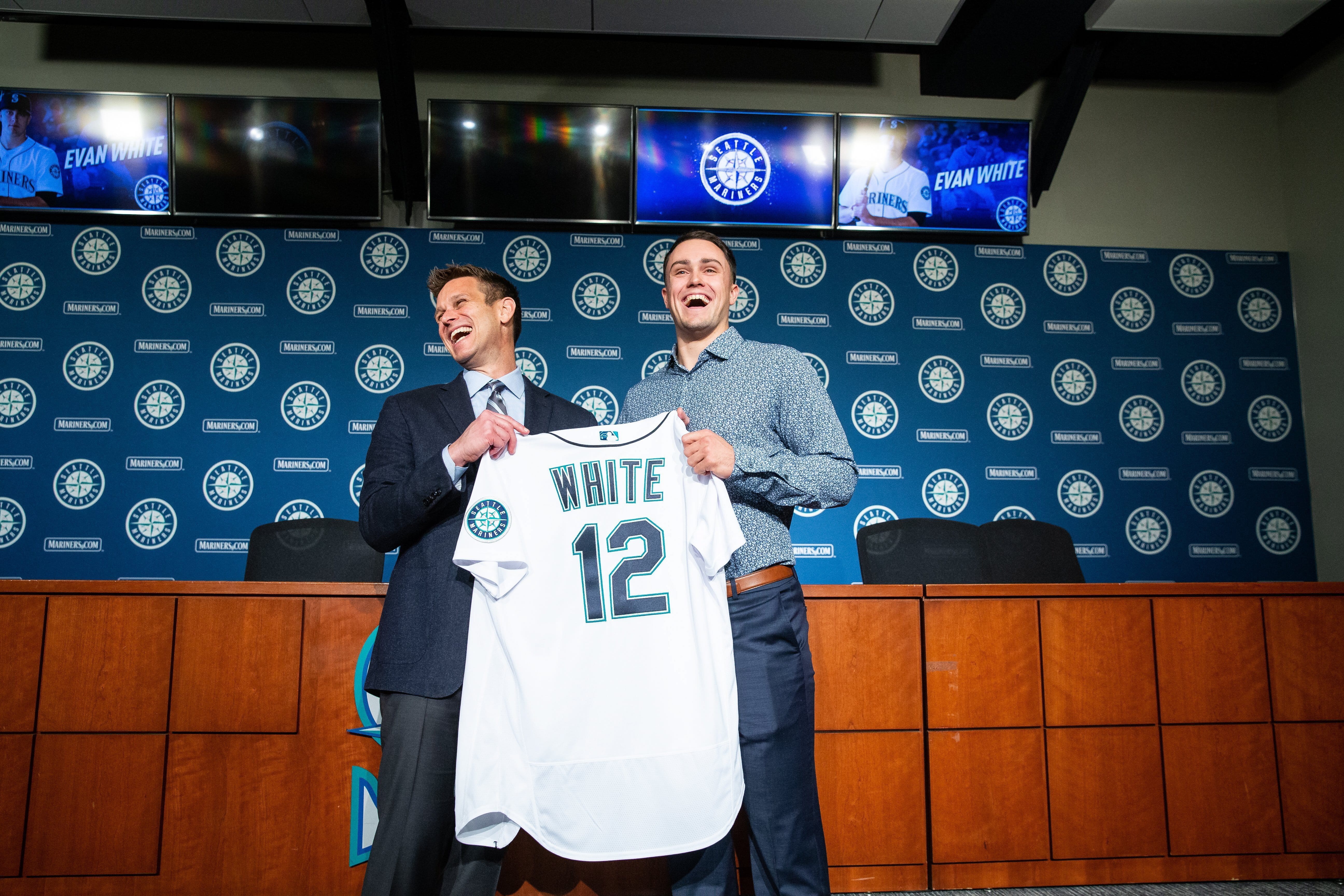 Seattle Mariners general manager Jerry Dipoto, left, and new first baseman Evan White pose for photographs with White's new jersey after a news conference at T-Mobile Park Monday, Nov. 25, 2019 in Seattle.