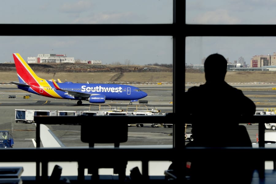FILE- In this Jan. 25, 2019, file photo a Southwest Airlines jet moves on the runway as a person eats at a terminal restaurant at LaGuardia Airport in New York. The National Transportation Safety Board is meeting Tuesday, Nov. 19  in Washington to consider the cause of a deadly engine failure on a Southwest Airlines flight last year. The incident killed a passenger who was blown partly out of the plane when a piece of the engine shattered the window next to her.