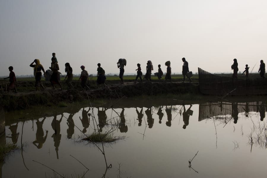 -FILE- In this Tuesday, Sept. 5, 2017, file photo members of Myanmar&#039;s Rohingya ethnic minority walk through rice fields after crossing the border into Bangladesh near Cox&#039;s Bazar&#039;s Teknaf area. Gambia has filed a case at the United Nations&#039; highest court in The Hague, Netherlands, Monday, Nov. 11, 2019, accusing Myanmar of genocide in its campaign against the Rohingya Muslim minority.