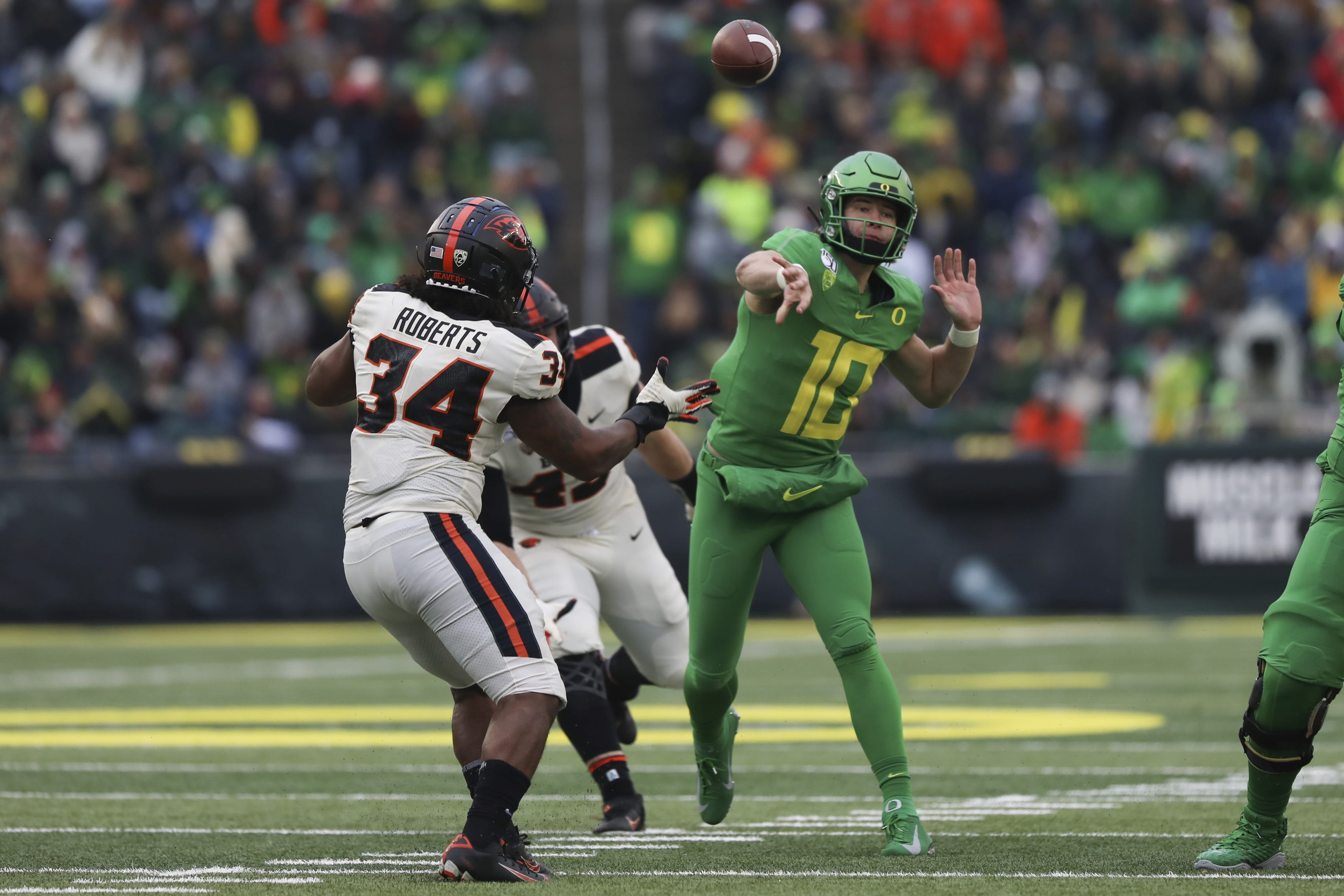 Oregon quarterback Justin Herbert (10) throws a pass away from Oregon State inside linebacker Avery Roberts (34) and defensive lineman Simon Sandberg (45) during the second half of an NCAA college football game in Eugene, Ore., Saturday, Nov. 30, 2019.
