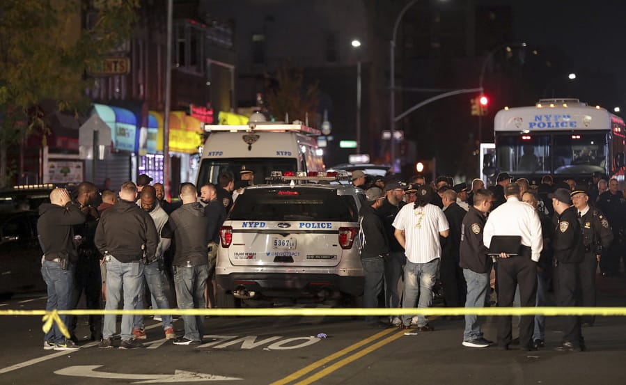 FILE - In this Oct. 25, 2019 file photo, New York police and other emergency personnel investigate the scene of a shooting at a nail salon in the Brownsville neighborhood of the Brooklyn borough of New York. Police say the man who attacked a police officer with a metal chair was shot to death by the officer. A surge in violent police clashes in recent weeks has left a trail of bodies across the city and stoked tensions between officers and critics who say they have been too quick to use deadly force.