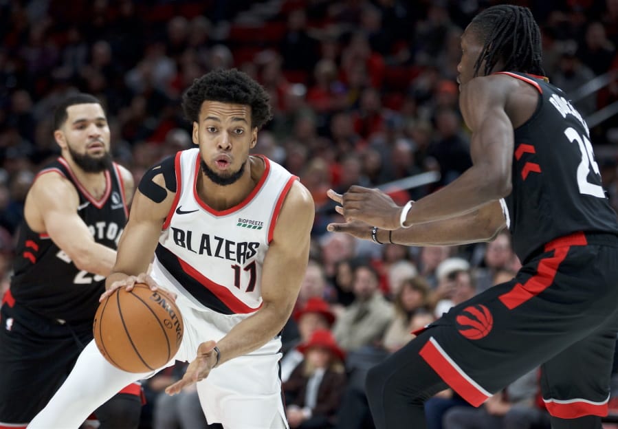 Portland Trail Blazers forward Skal Labissiere, center, dribbles around Toronto Raptors forward Chris Boucher, right, during the first half of an NBA basketball game in Portland, Ore., Wednesday, Nov. 13, 2019.