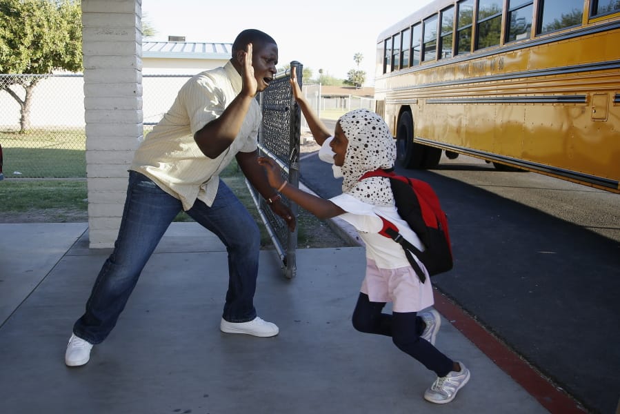 Samuel Lavi, left, a Congolese native who is a teaching assistant and family engagement liaison, greets first-grader Kediga Ahmed as she arrives Oct. 17 at Valencia Newcomer School in Phoenix. (Ross D.