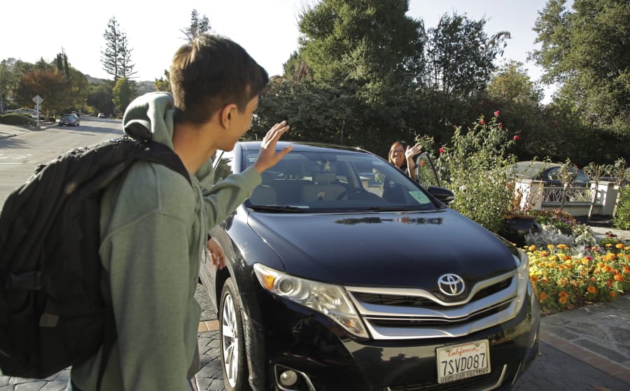 In this photo taken Tuesday, Oct. 29, 2019, Zum driver Stacey Patrick, right, waves goodbye to student Saahas Kohli, left, as he returns home from school in Saratoga, Calif. A handful of ride-hailing companies have surfaced that allow parents to order rides, and in some cases childcare, for children using smartphone apps. The promise is alluring at a time when children are expected to accomplish a dizzying array of extracurricular activities and the boundaries between work and home have blurred. But the companies face hurdles convincing parents that a stranger hired by a ride-hailing company is trustworthy enough to ferry their most precious passengers.