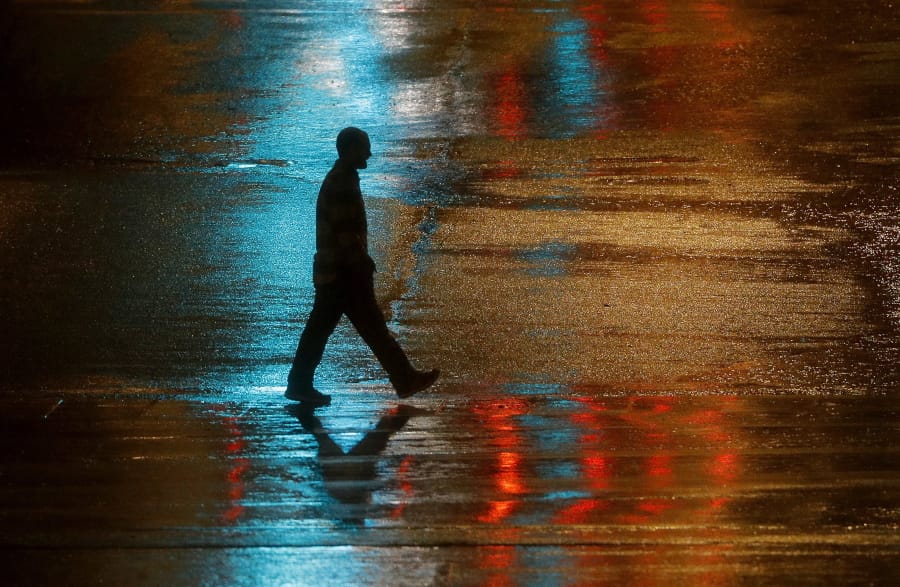 FILE - In this Wednesday, Dec. 26, 2018 file photo, a pedestrian is silhouetted against wet pavement in Kansas City, Mo. In a first-of-its-kind report released Tuesday, Nov. 5, 2019, the Centers for Disease Control and Prevention estimates that millions of cases of heart disease and other illnesses can be linked to abuse and other physical and psychological harm that patients suffered as children.