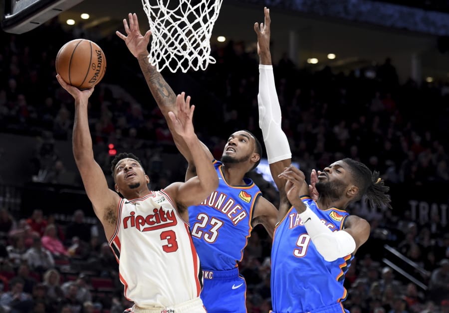 Portland Trail Blazers guard CJ McCollum, left, drives to the basket as Oklahoma City Thunder guard Terrance Ferguson, center, and center Nerlens Noel, right, defend during the second half of an NBA basketball game in Portland, Ore., Wednesday, Nov. 27, 2019. The Blazers won 136-119.