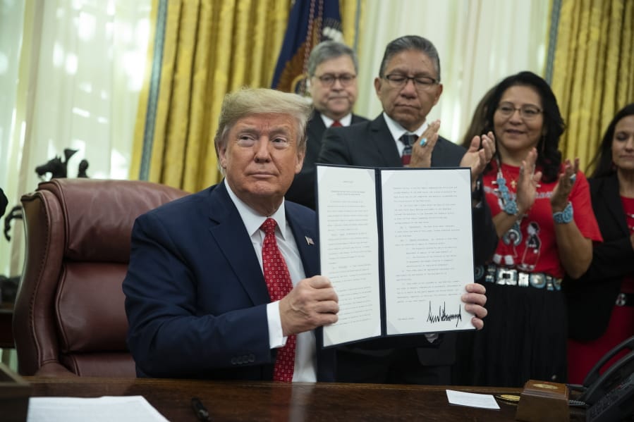 President Donald Trump shows an executive order establishing the Task Force on Missing and Murdered American Indians and Alaska Natives, in the Oval Office of the White House, Tuesday, Nov. 26, 2019, in Washington.