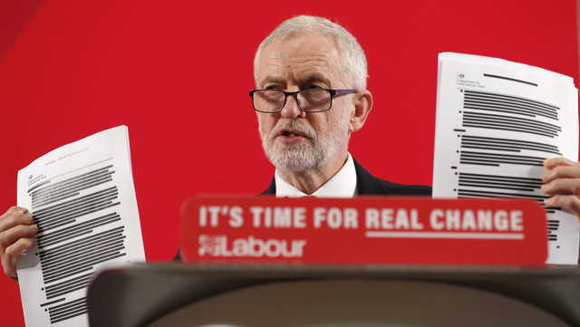 Britain's Labour party leader Jeremy Corbyn shows blacked out papers as he delivers a speech in London, England, Wednesday, Nov. 27, 2019, ahead of the general election on Dec. 12.