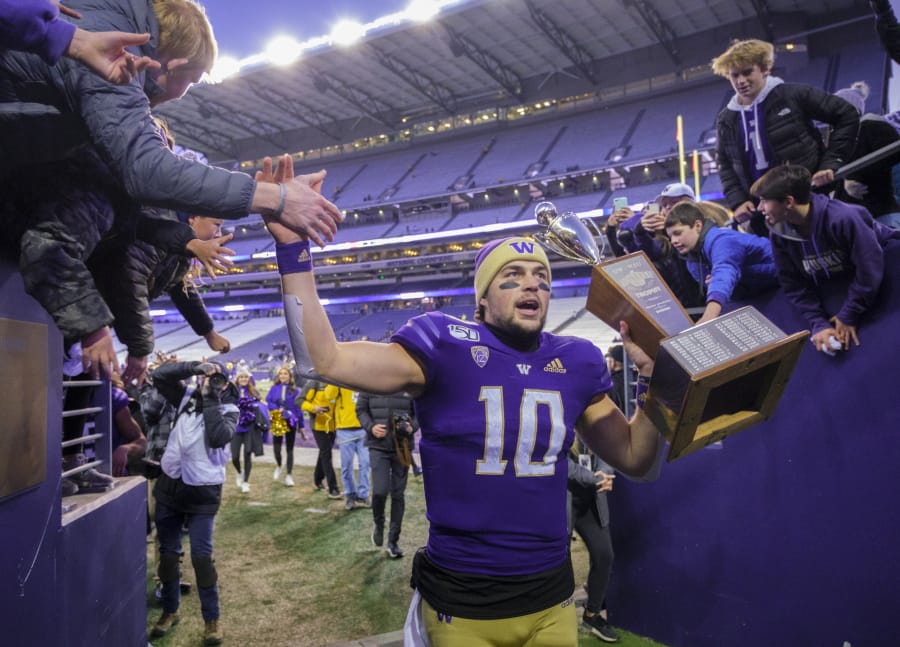 Washington quarterback Jacob Eason high fives fans as he leaves the field with the Apple Cup after an NCAA college football game against Washington State, on Friday, Nov. 29, 2019 in Seattle. Washington won 31-13.