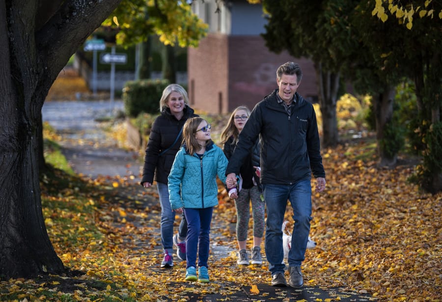Sarah, from left, Vivian, Lucy and Chris Collmer walk their dog, Teddy, in the Hough neighborhood of Vancouver. The Collmer family tries to walk for excursions downtown to reduce carbon emissions. Sarah Collmer said they have come to really enjoy this time together. &quot;You notice more things and connect with the community more,&quot; she said.