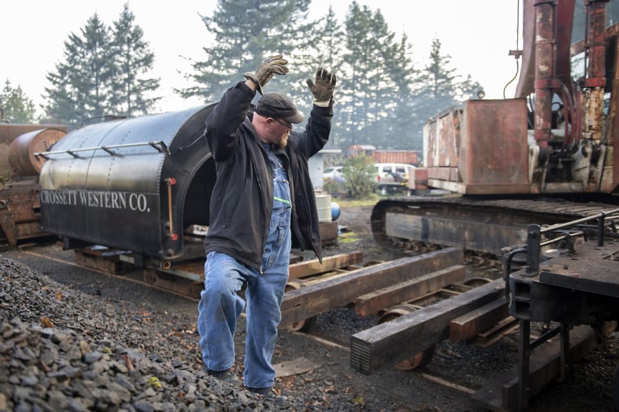 Matt Barton, vice president of the Chelatchie Prairie Railroad Association, signals that the engineer inching a locomotive along is running out of clear track. Behind Barton is the saddle-style water tank that was lifted off the group&#039;s 1929 steam engine during the federally mandated inspection.