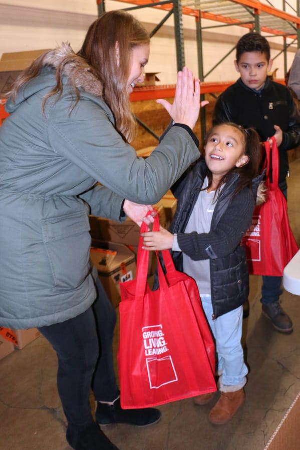 EAST VANCOUVER: Lilly Kovalenko high-fives Cali Lumbreras. More than 60 volunteers recently helped put together more than 1,000 packs to donate to those who are homeless or living in poverty at Share Vancouver.
