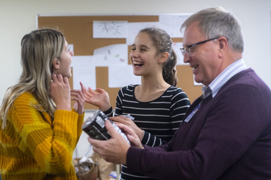 Ella Galloway, 12, from left, Joanna Sokolova, 12, and problems-based learning teacher Kent Graham talk about using a plastic bottle as a building while creating a model of a city with a futuristic water filtration system Friday afternoon at River HomeLink.