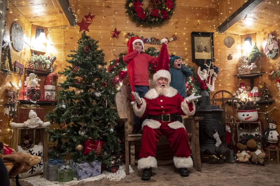 Connar Williams, 11, from left, Santa Claus, played by Brian Trembley, and Gage Williams 6, pose for a photo in Trembley&#039;s Santa Chalet in Woodland.