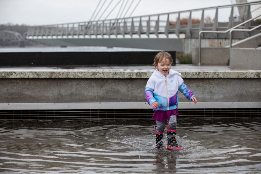 Ellie Adams, 2, of Vancouver plays in a large puddle Saturday afternoon at an otherwise inactive water feature at The Waterfront Vancouver.