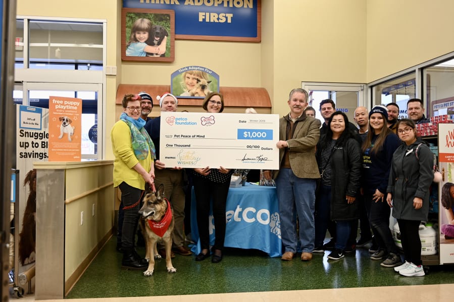 CASCADE PARK WEST: Dr. Emily Huber is with her dog, Woofy, while Dianne McGill, Pet Peace of Mind founder/president, middle, and Dr. Bob Lester, Pet Peace of Mind board of directors and chief medical officer at WellHaven Pet Health, right, hold the check. WellHaven Pet Health employees and Pet Peace of Mind supporters joined in at the Dec. 17 event at Petco, 305 S.E.