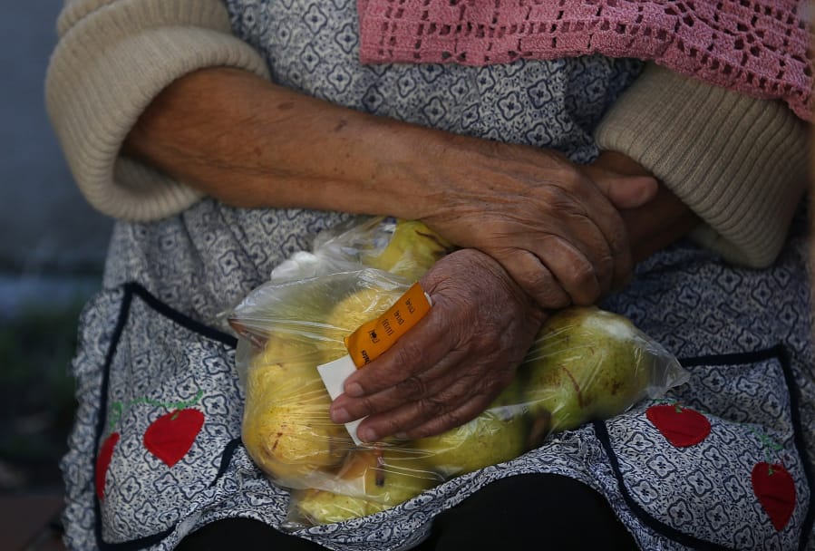 A woman holds a bag of pears as she waits in line at the Richmond Emergency Food Bank on Nov. 1, 2013 in Richmond, Calif. The Trump administration will announce a plan Wednesday to end food stamp benefits for about 750,000 Americans.