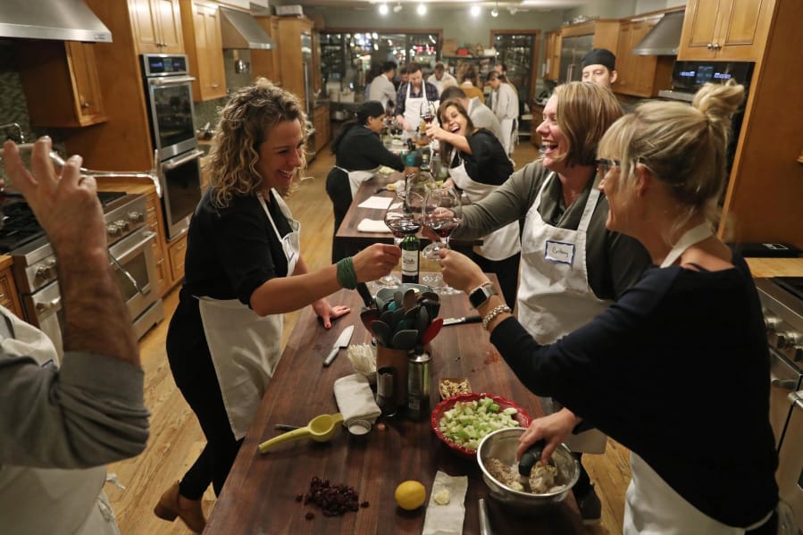 Guests Tarra Bathurst, clockwise from left, Brittany Georgiou and Sarah Schlichte clink their wine glasses during a dinner instruction course titled, &quot;Steakhouse DIY&quot; at the Chopping Block in Chicago. (John J.