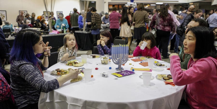 Families share a table to dine on latkes, hummus, pita and vegetables during Temple Israel&#039;s Hanukkah Latke Party on Dec. 20 at the Jewish Community Center of Greater Columbus in Columbus, Ohio.