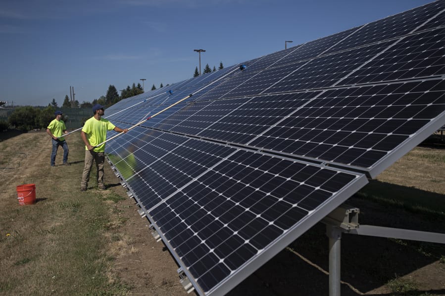 Nick Neathamer, left, and Rafer Stromme, members of the student grounds crew, clean solar panels at Clark Public Utilities in 2019. The panels need to be cleaned to remove dust to maximize energy production.