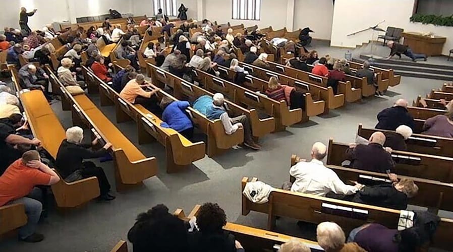 In this still frame from livestreamed video provided by law enforcement, churchgoers take cover while a congregant armed with a handgun, top left, engages a man who opened fire, near top center just right of windows, during a service at West Freeway Church of Christ, Sunday, Dec. 29, 2019, in White Settlement, Texas. The footage was broadcast online by the church according to a law enforcement official, who provided the image to The Associated Press on condition on anonymity because the investigation is ongoing.