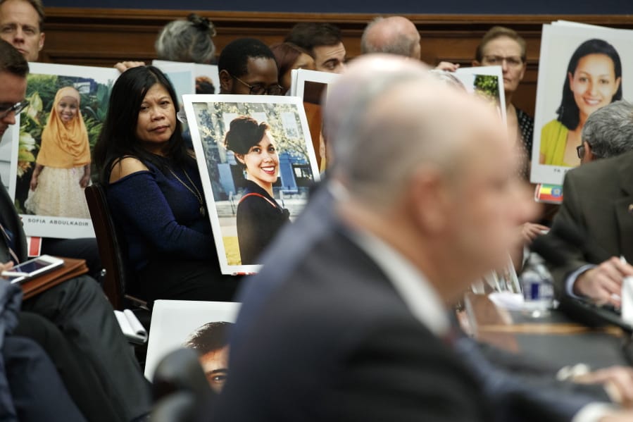 Family members of people who died in crashes of the Boeing 737 MAX hold photographs of their lost loved ones as FAA Administrator Stephen Dickson testifies during a House Transportation Committee hearing on the Boeing 737 MAX, Wednesday, Dec. 11, 2019, on Capitol Hill in Washington.