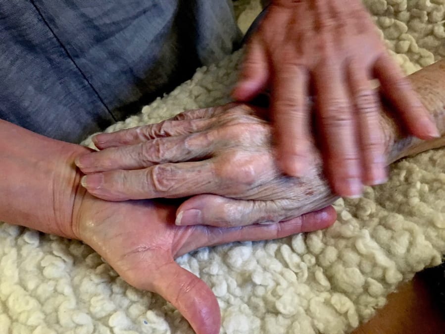 Allison Beach holds the hand of her ailing mother, Kathryne Beach, in her home in Hinesburg, Vt., in 2016. Kathryne Beach lived with her daughter for three years and died at home.