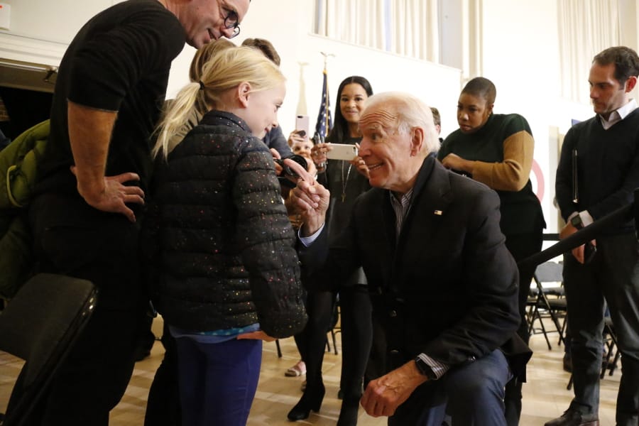 Democratic presidential candidate former Vice President Joe Biden kneels to greet Sydney Hansen, 9, of Oakland, Calif., during a campaign stop on Sunday, Dec. 29, 2019, in Peterborough, N.H.